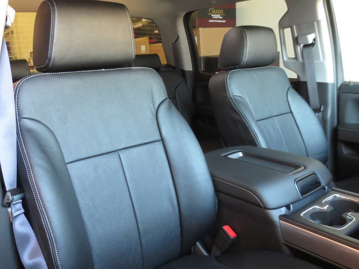 A close-up of the front passenger and driver's seats in a car, featuring black leather upholstery with white stitching and Clazzio custom seat covers. The image also shows a sleek center console.